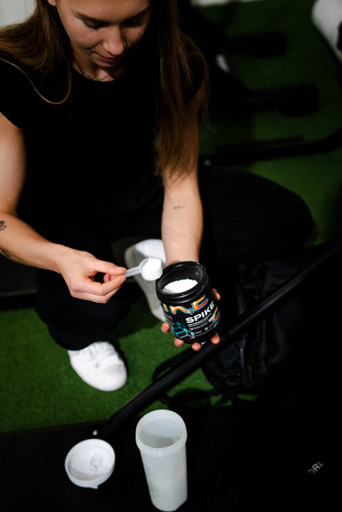 Girl scooping Spike (Citrulline + Glycerol) into a Supplement World Shaker. 